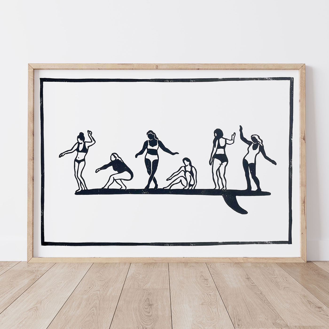 Framed lino print artwork with black line drawings of 6 women surfing together on one board, celebrating the sense of support and community from women in the water.