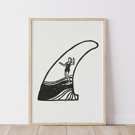 Framed artwork of a black silhouette of a person surfing inside the silhouette of a surf fin